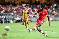 Micheal Udebuluzor in Hong-Kong-Trikot kicks ball mid-match